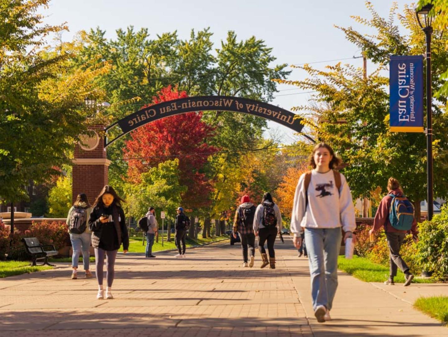 Students walking along 澳门葡京网赌送彩金 pathway in autumn foliage 